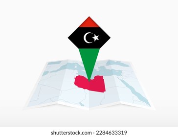 Libyen wird auf einer gefalteten Papierkarte und einem eingeklemmten Ortsmarkierungszeichen mit libyscher Flagge dargestellt. Gefalte Vektorkarte.