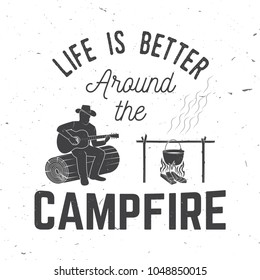 Life is better around the campfire. Vector illustration. Concept for shirt or logo, print, stamp or tee. Vintage typography design with campfire, pot on the fire, man with guitar silhouette.