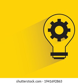 light bulb and gear with shadow on yellow background