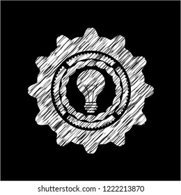 light bulb icon inside chalk emblem written on a blackboard