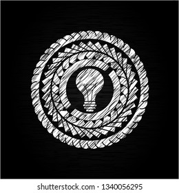 light bulb icon inside chalkboard emblem written on a blackboard