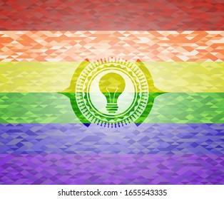 light bulb icon inside emblem on mosaic background with the colors of the LGBT flag