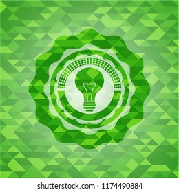 light bulb icon inside green emblem. Mosaic background