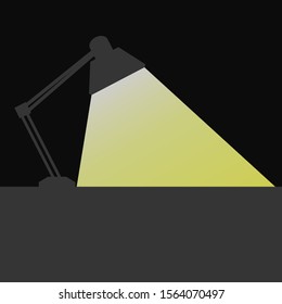 
The light from the lamp shines down at the desk in a dark room.