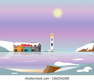 Lighthouse and houses standing on the island in the sea against the backdrop of the mountains. Winter.