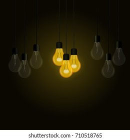 Lighting bulbs among other light bulbs on a dark background