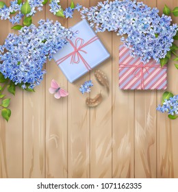 Lilac on wooden background. Spring top view composition with blossoming tree branches, gifts, feathers and butterfly