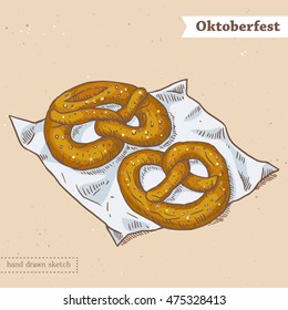 Linear colored sketch of the tasty pretzels on the napkin with text Oktoberfest. Hand drawn vintage vector illustration with german traditional food on the textured beige paper background.