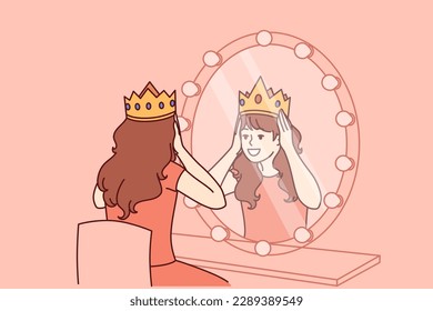 Little actress tries on crown sitting in dressing room with mirror and dreams of playing role of princess on theater stage. Teenage girl puts princess crown on head dreaming of living among kings 