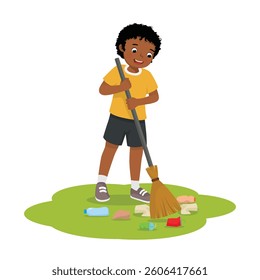 Little African boy sweeping trash in the yard with broom