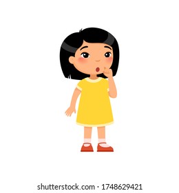 Little asian girl showing silence gesture flat vector illustration. Child in dress standing, thinking cartoon character. Kid with confused face expression considering. Quiet sign