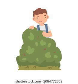 Niño pequeño con mochila en el jardín escolar cerca de la ilustración del vector Bush verde
