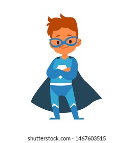 Little boy in blue superhero costume standing folded arms cartoon style, vector illustration isolated on white background. Boy child dressed in cape and mask in brave heroic pose with crossed arms