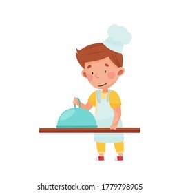 Little Boy Character in Hat and Apron Standing at Kitchen Table Cooking Dish Vector Illustration
