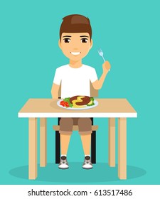 Little boy eats sitting at the dining table. Holding a fork in his hand. Food. Happy boy