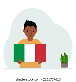 A little boy holds the flag of Italy in his hands. The concept of demonstration, national holiday or patriotism. Nationality.