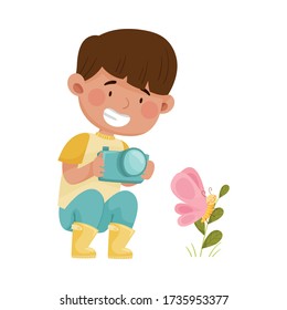 Little Boy Hunkering Down with Camera Taking Photo of Butterfly Sitting on Grass Vector Illustration