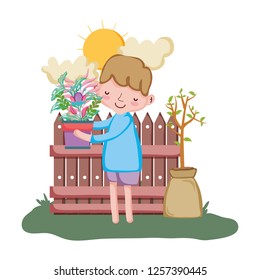 little boy lifting houseplant with fence in the garden