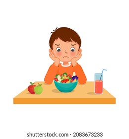 Un niño picky come sintiéndose infeliz mirando el tazón de frutas y verduras negándose a comer. 