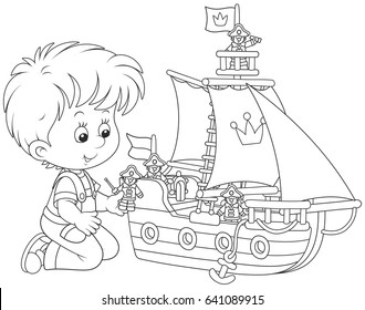 Little boy playing a toy sailing ship