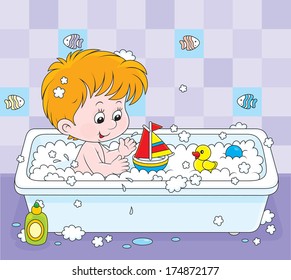 Little boy playing with toys in a bath with foam