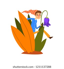 Little boy in a pointed striped hat walking in tall grass, cute fairy creature on beautiful natural landscape vector Illustration on a white background