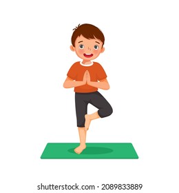 Little boy practicing yoga pose on a green mat indoor at home