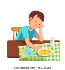 A little boy refusing food, kid does not want to eat. Kid sits at the table and does not want to eating