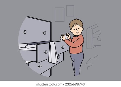 Little boy is standing near closet with clothes, looking at textiles with curiosity and studying world around. Childish pranks of funny boy throwing clothes from drawer making mess while playing