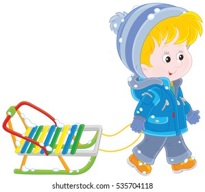 Little boy walking with his sled