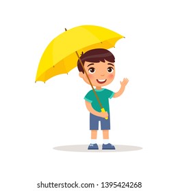 Little  boy with yellow umbrella smiles and waves his hand. Male child standing cartoon character. Rainy weather concept. Summer or fall season. Flat vector illustration. Isolated on white backgr