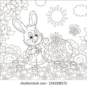 Little bunny coloring a big Easter egg on grass among flowers on a sunny spring day, black and white vector illustration in a cartoon style