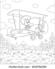 Little cheerful boy piloting his small toy plane among clouds in summer sky over a park near cute town houses on a sunny day, black and white outline vector cartoon illustration for a coloring book pa