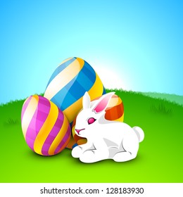 Little cute Easter rabbit with painted eggs on nature background.