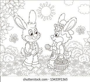 Little Easter Bunnies exchanging colored eggs on a lawn among flowers and flittering butterflies on a sunny spring day, black and white vector illustration in a cartoon style for a coloring book