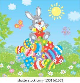Little Easter Bunny on a pile of colorfully decorated eggs on green grass on a sunny spring day, vector illustration in a cartoon style