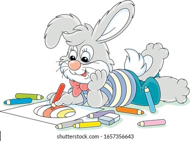 Little Easter bunny smiling and drawing a decorated holiday egg with color pencils on a sheet of paper for a greeting card, vector cartoon illustration on a white background