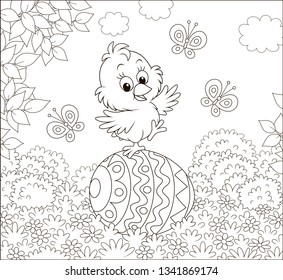 Little Easter Chick dancing on a big decorated egg on a lawn on a sunny spring day, black and white vector illustration in a cartoon style for a coloring book