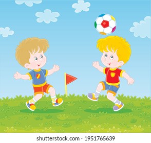 Little football players with a colorful ball at a match or training on a green sports field on a bright summer day, vector cartoon illustration