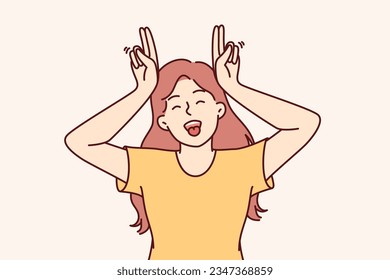 Little funny girl makes horns from fingers and shows tongue, wanting to cheer up others and friends. Teenage girl laugh making comical grimace and fool around refusing to become adult