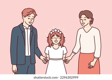 Little girl along with father and mother on day of holy communion according to christian catholic traditional rite. Preteen girl in white elegant dress participates in communion ceremony with parents