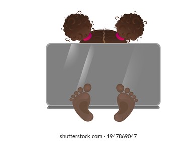 Little girl behind laptop, only top of the head with curly brunette buns are visible and cute little feet.