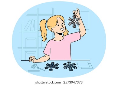 Little girl cuts out paper snowflakes preparing handmade christmas decorations for home on eve of new year. Child stands near table with scissors demonstrating snowflake made with own hands