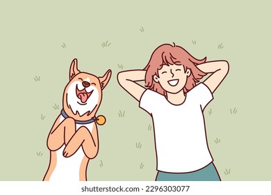 Little girl and dog lie on grass in backyard of house and enjoy sunny summer day. Laughing teenage girl with red dog shiba inu relaxing on lawn enjoying local pastime during vacation