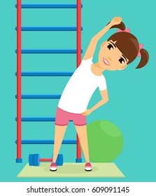 Little girl doing sport exercises in the gym. The promotion of health. The girl is engaged in gymnastics. Gymnastic ball, a dumbbell, Swedish wall.