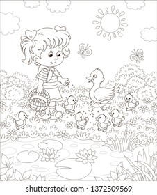 Little girl feeding a duck and small ducklings among flowers by a pond with water-lilies on a sunny summer day, black and white vector illustration in a cartoon style