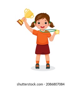 Little girl holding up a gold cup trophy and medal celebrating winning competition