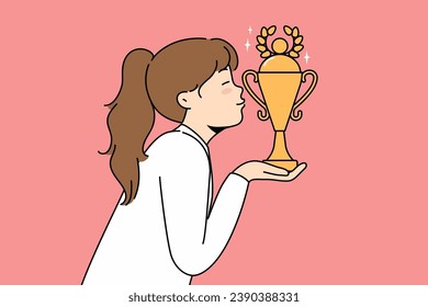 Little girl leader kisses golden cup won in school olympiad or sports competition. Schoolgirl leader with trophy received for achievements in education or outstanding athletic skills