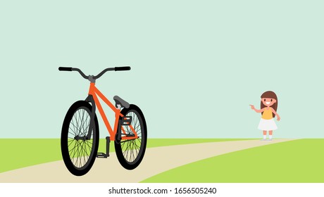 Little girl points a finger at bicycle, against the background of the road and a green meadow