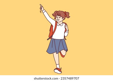 Little girl runs to school with backpack, joyfully raises hand, seeing classmates. Happy schoolgirl hurries to school for beginning of lesson so as not to upset teacher and get positive grades